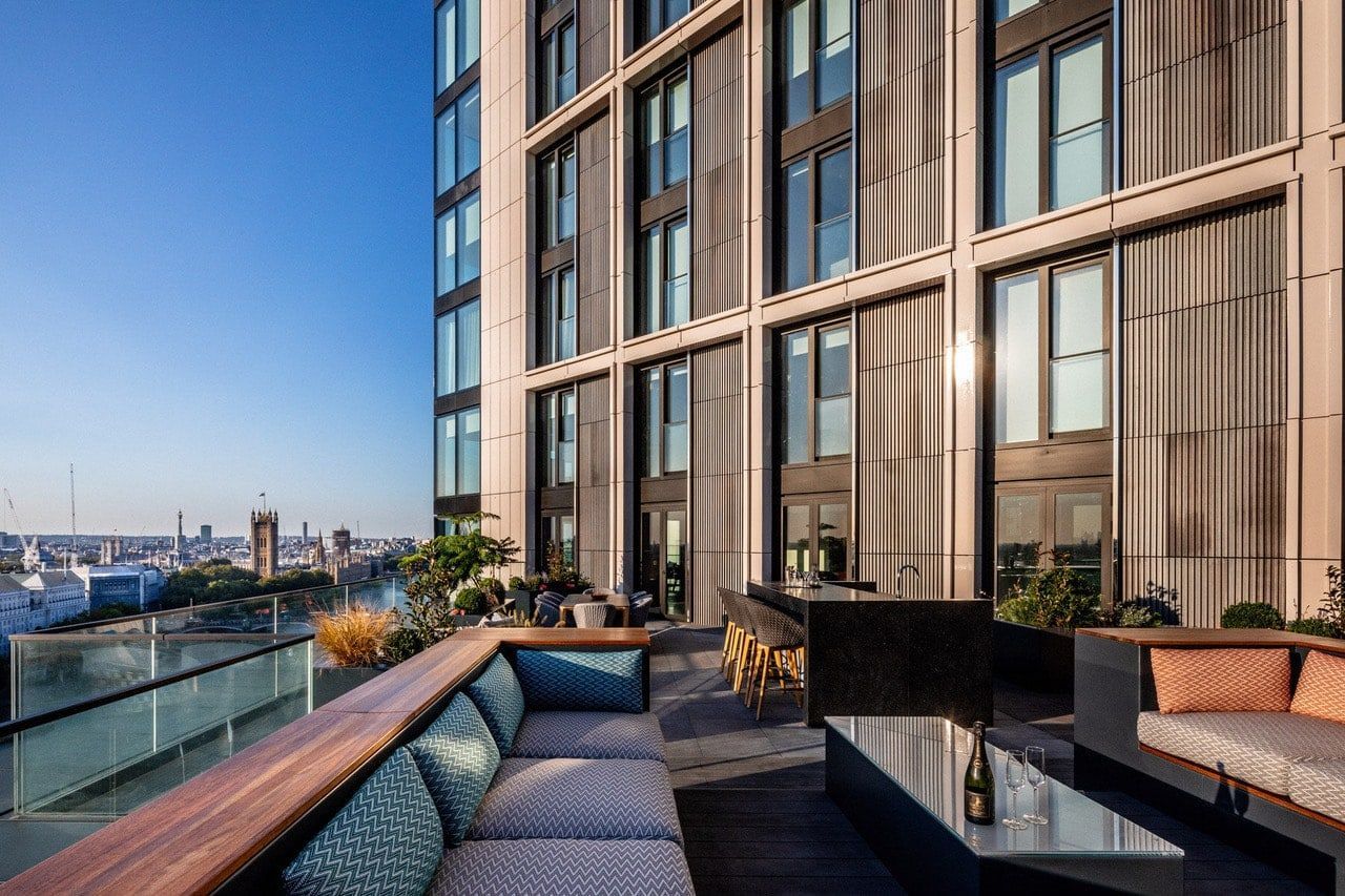 Rooftop patio with seating overlooking a city skyline. Modern high-rise building in the background.