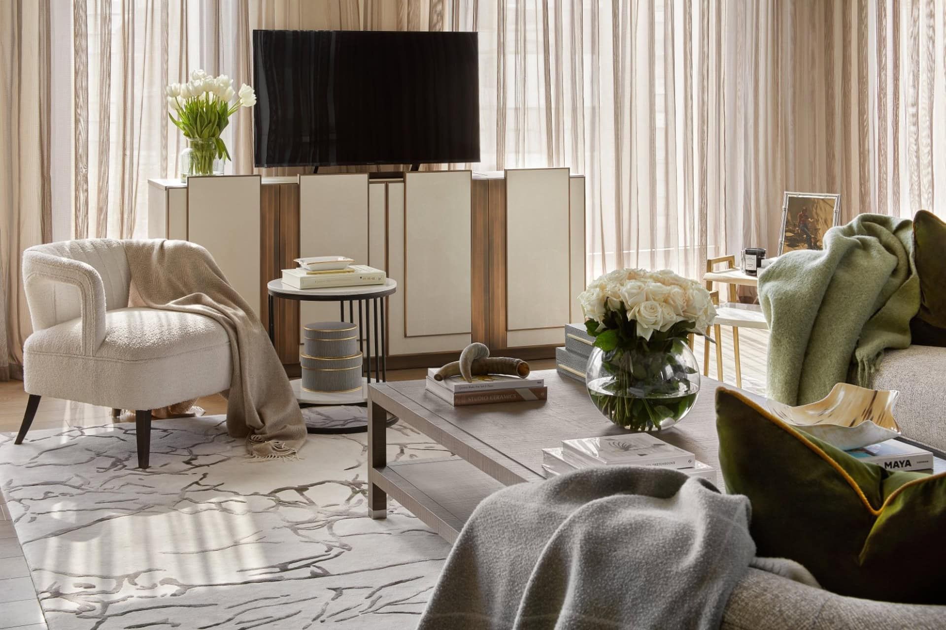 Living room with white armchair, large TV on a cabinet, coffee table, and green sofa.