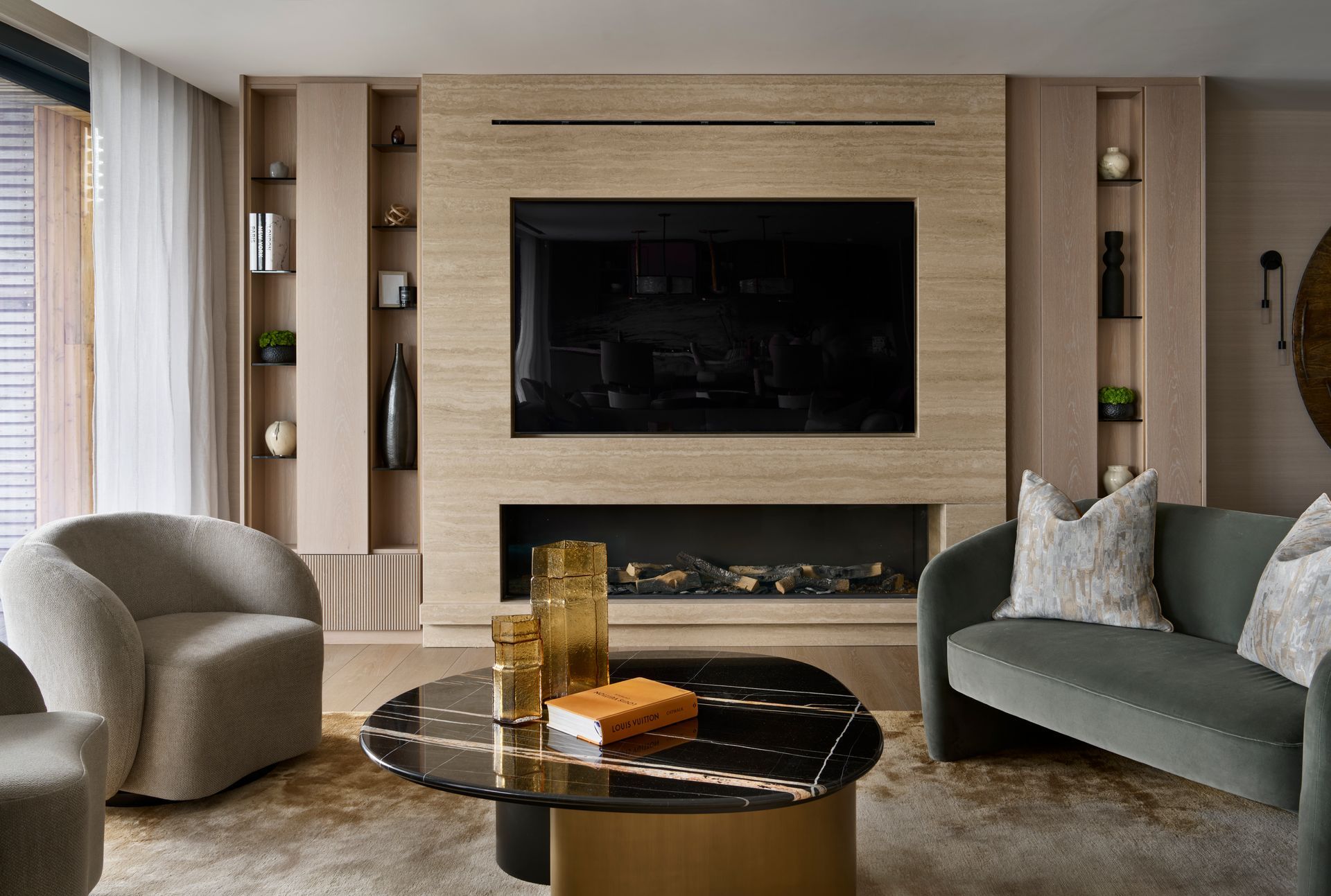 Living room with built-in TV, fireplace, teal sofa, and beige accent chairs.