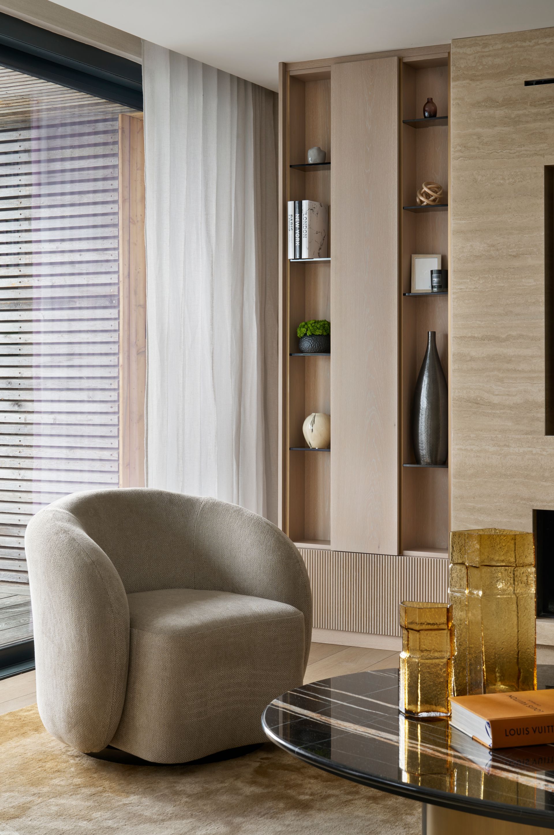 Cozy living room with a beige rounded chair, built-in shelves, and a black coffee table.
