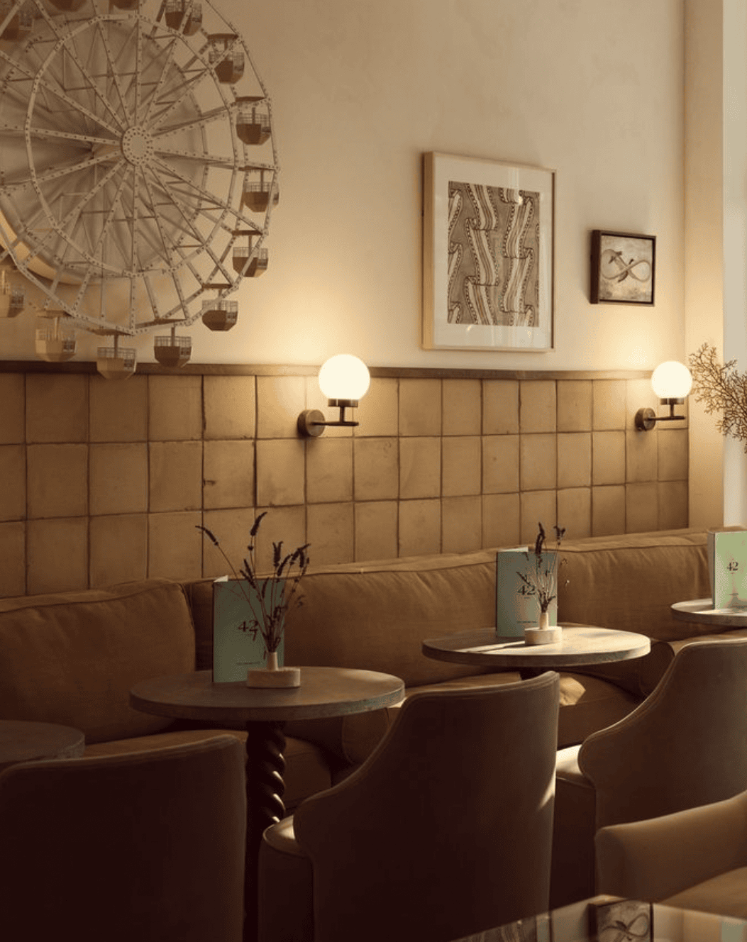 Cozy cafe with a Ferris wheel decoration, banquette seating, round tables, and sconce lighting.