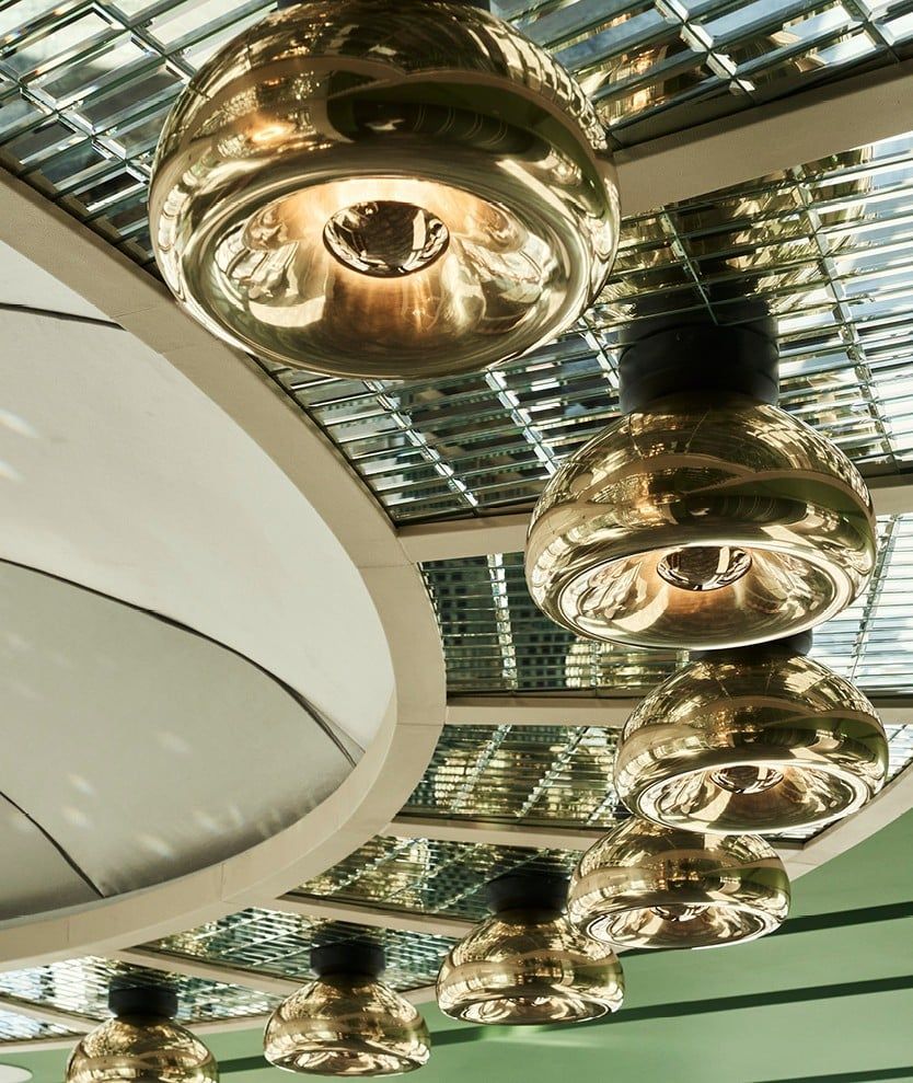 Golden pendant lights hanging from a mirrored ceiling, angled view.