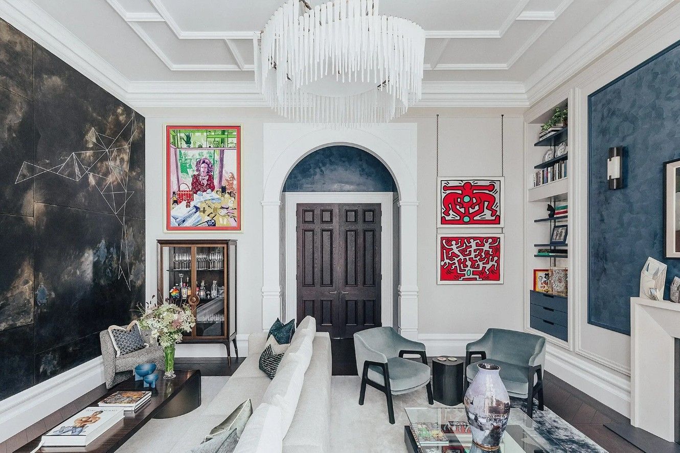 Living room with dark marble wall, TV, art, light sofa, and chandelier.