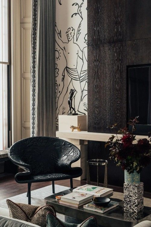 Living room with a black chair, patterned wallpaper, and a dark fireplace.