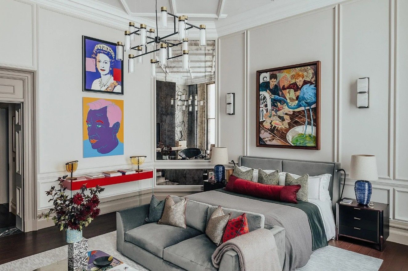 Elegant bedroom with colorful art, a gray sofa, and a large bed.