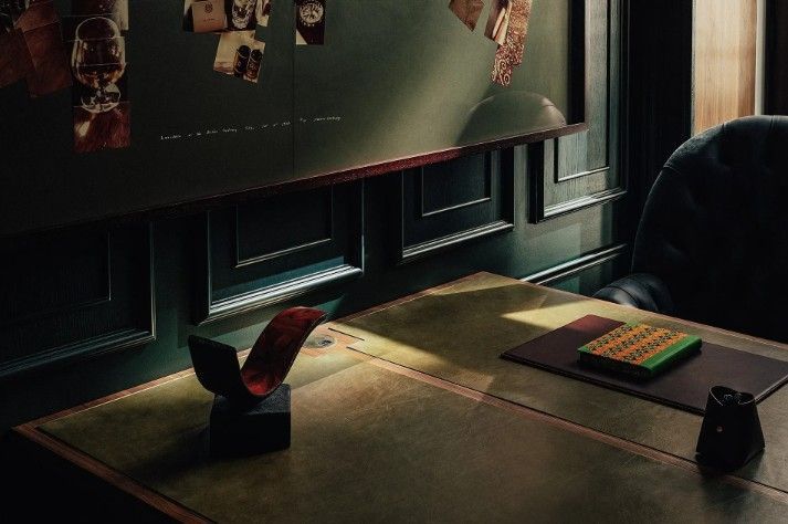 Office desk with dark wood paneling, a red sculpture, and a green box.