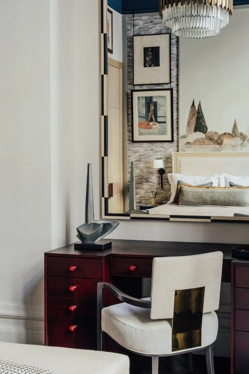 Bedroom with red desk, artwork, and a modern chair.