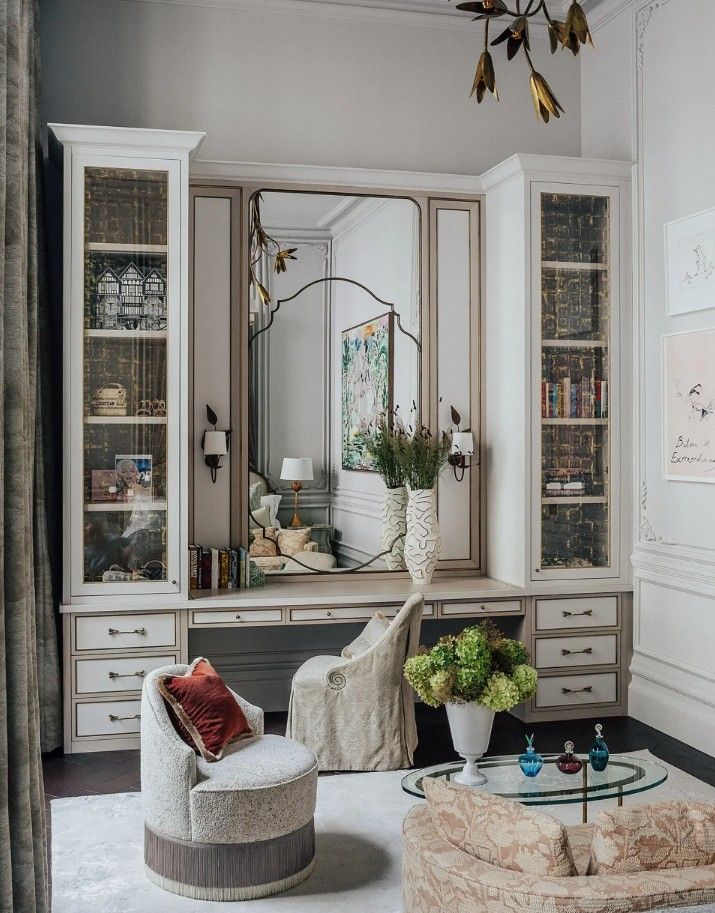 Vanity with cabinets and large mirror, floral bouquet, armchair, and sofa in a bright room.