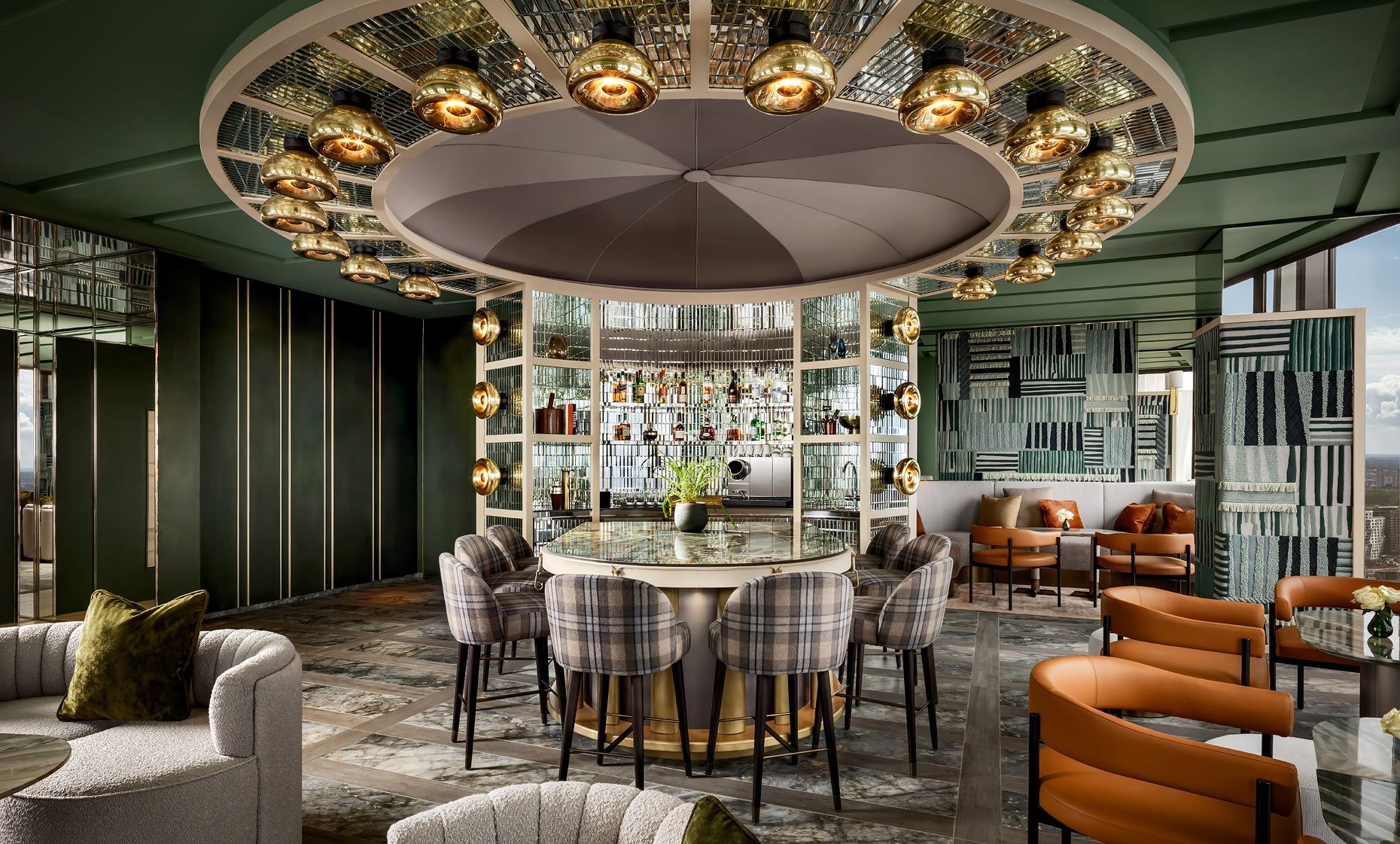 Circular bar with stools, gold accents, and a display of liquor bottles, within a stylish lounge.