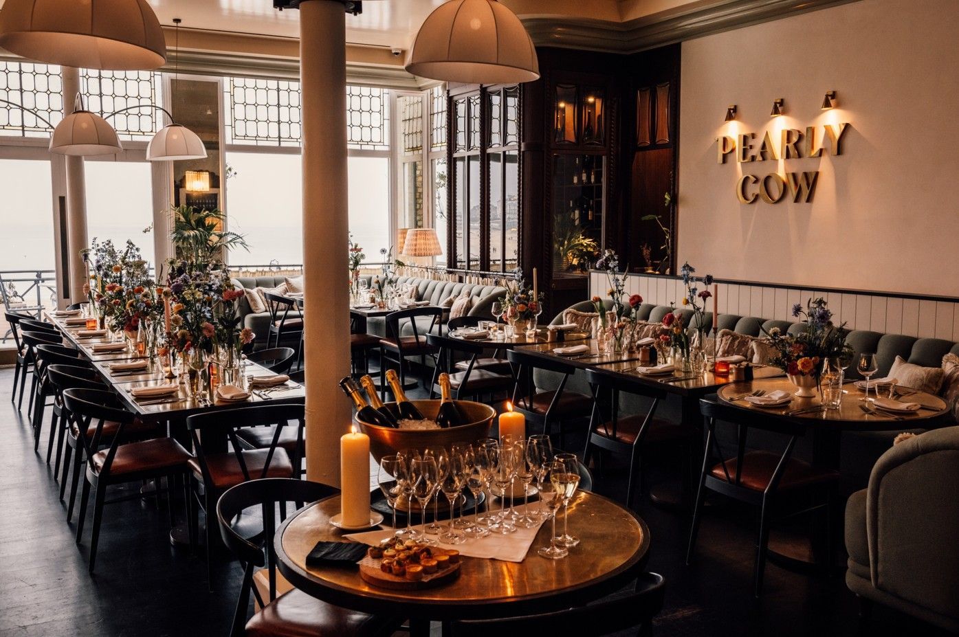 Elegant restaurant interior with long tables, a round table, and the sign