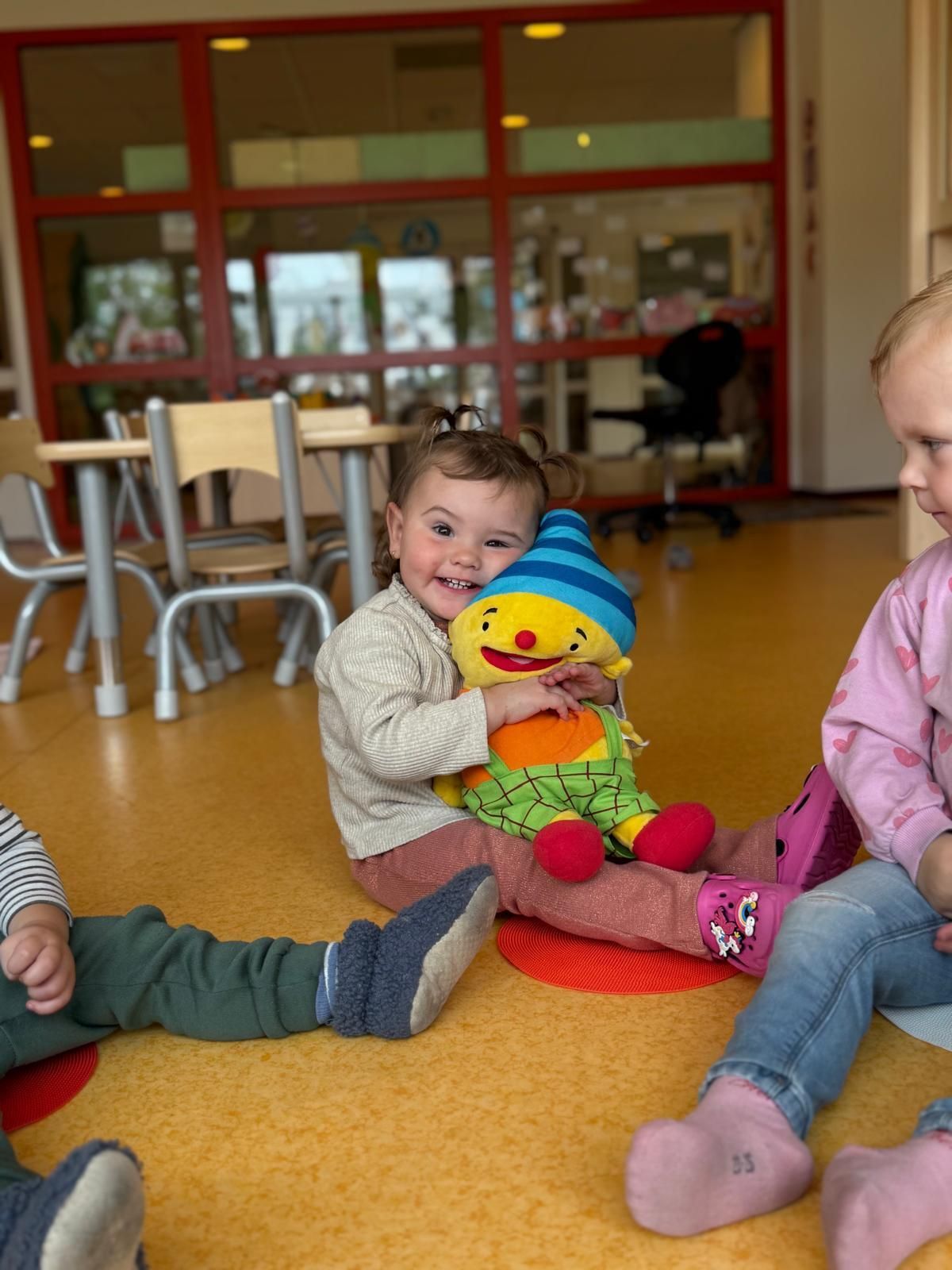 Kinderen zitten op een kleurrijke speelkamervloer
