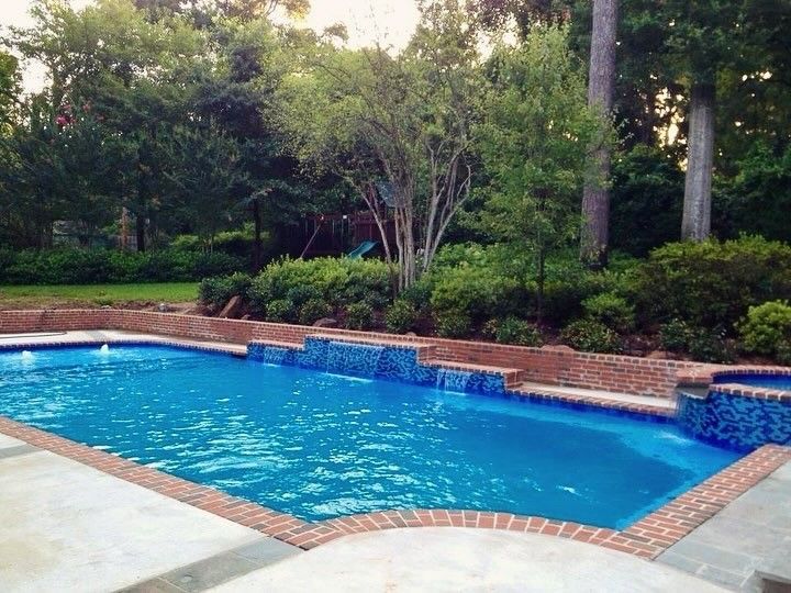 A large swimming pool is surrounded by lawn chairs and a building.