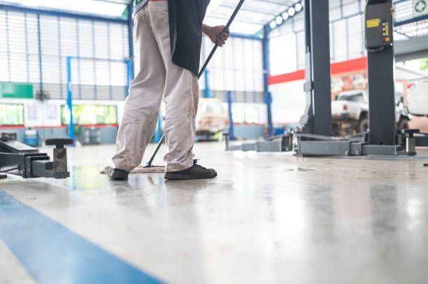 A man is cleaning the floor of a garage with a mop.