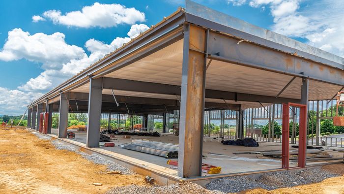 Construction site of a building with steel frame and concrete floor, blue sky.