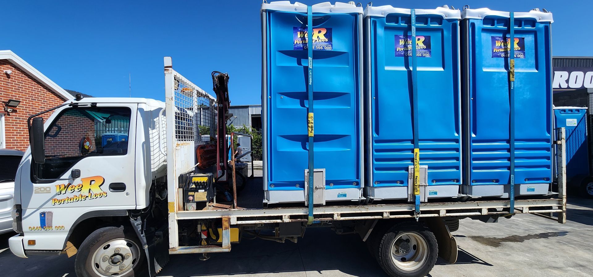 Blue portable toilet truck parked on a street beside a building and fence — Wee R Pumping In Glenorchy, TAS