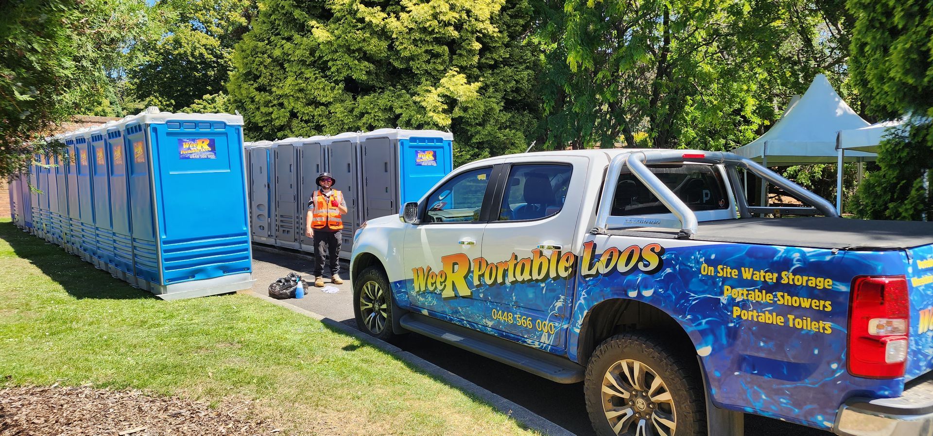 Blue pickup truck and container units at an outdoor event, with a person standing by the containers — Wee R Pumping In Glenorchy, TAS