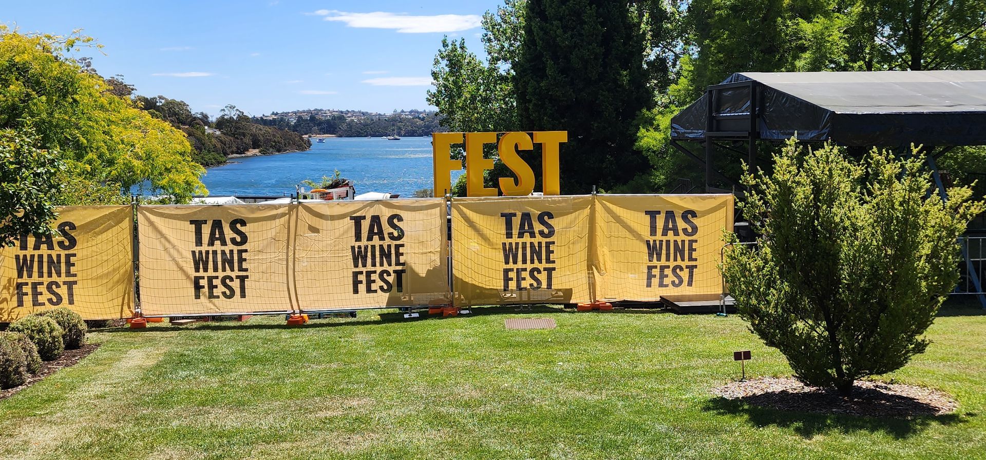 Outdoor TAS Wine Fest signs and a large yellow FEST banner on a grassy lawn under a blue sky — Wee R Pumping In Glenorchy, TAS