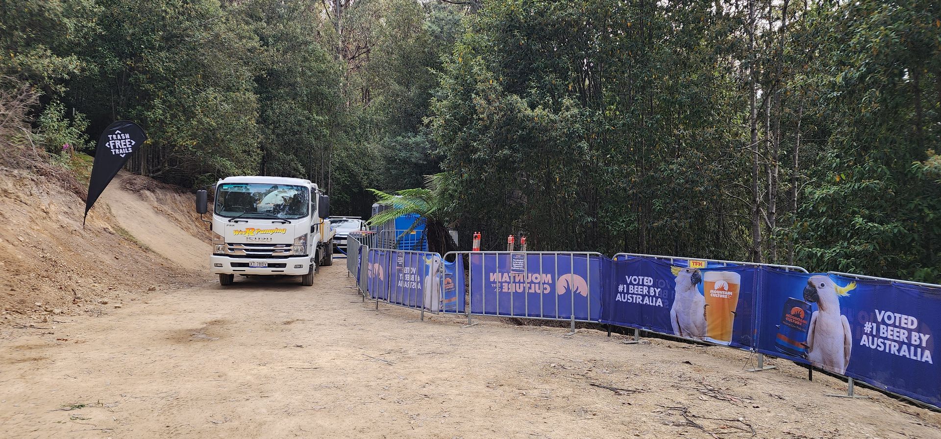 Bus on a dirt road beside blue barriers and trees — Wee R Pumping In Glenorchy, TAS