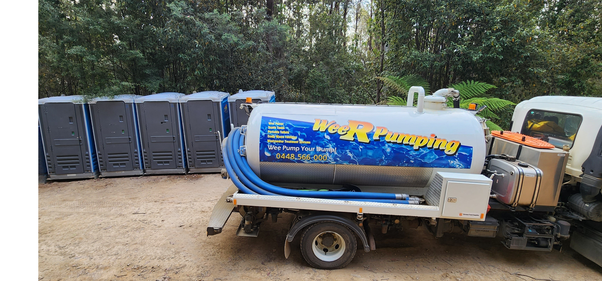 Portable toilets lined up beside a blue water truck and trailer in a gravel yard — Wee R Pumping In Glenorchy, TAS
