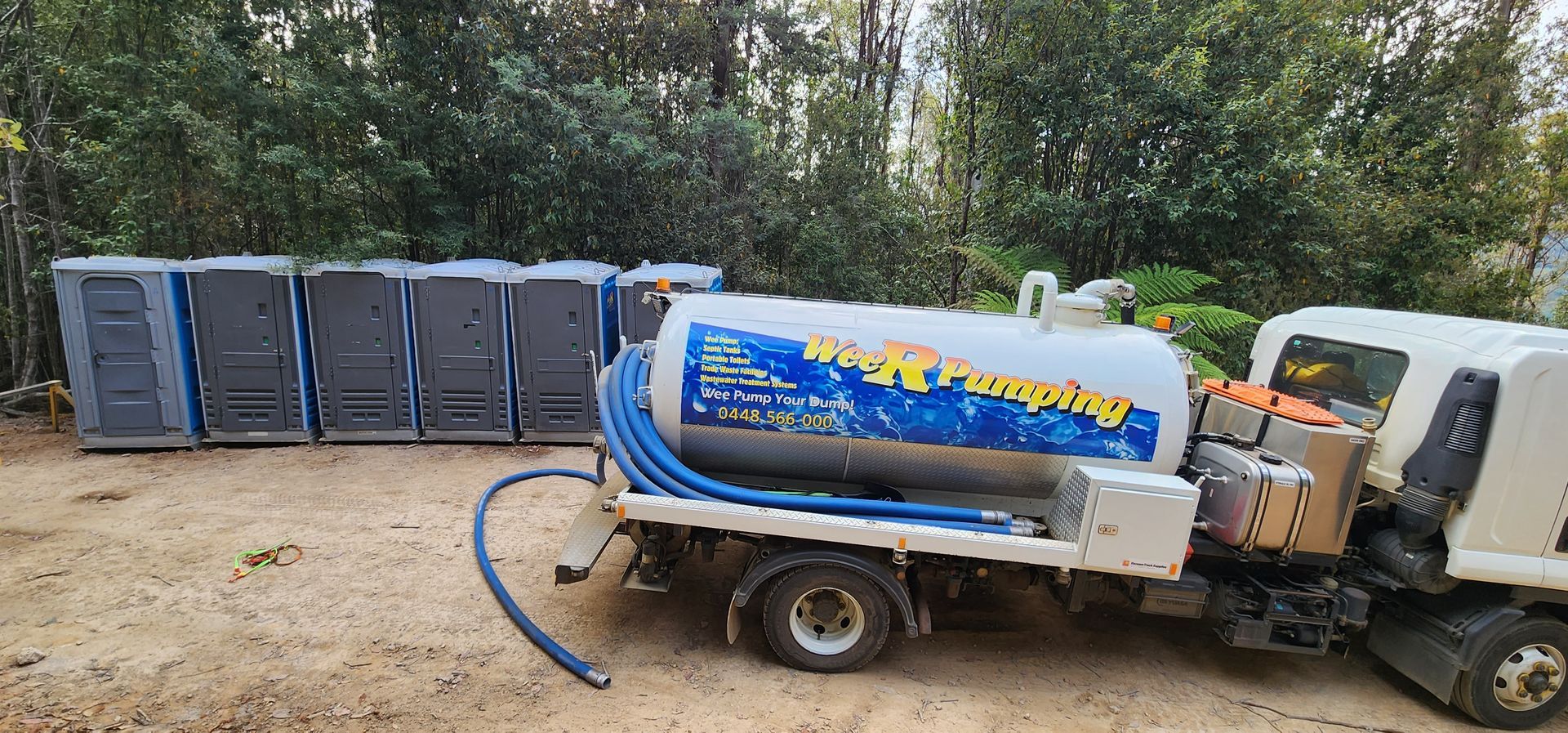 Blue septic truck beside row of portable toilets on a dirt lot — Wee R Pumping In Glenorchy, TAS
