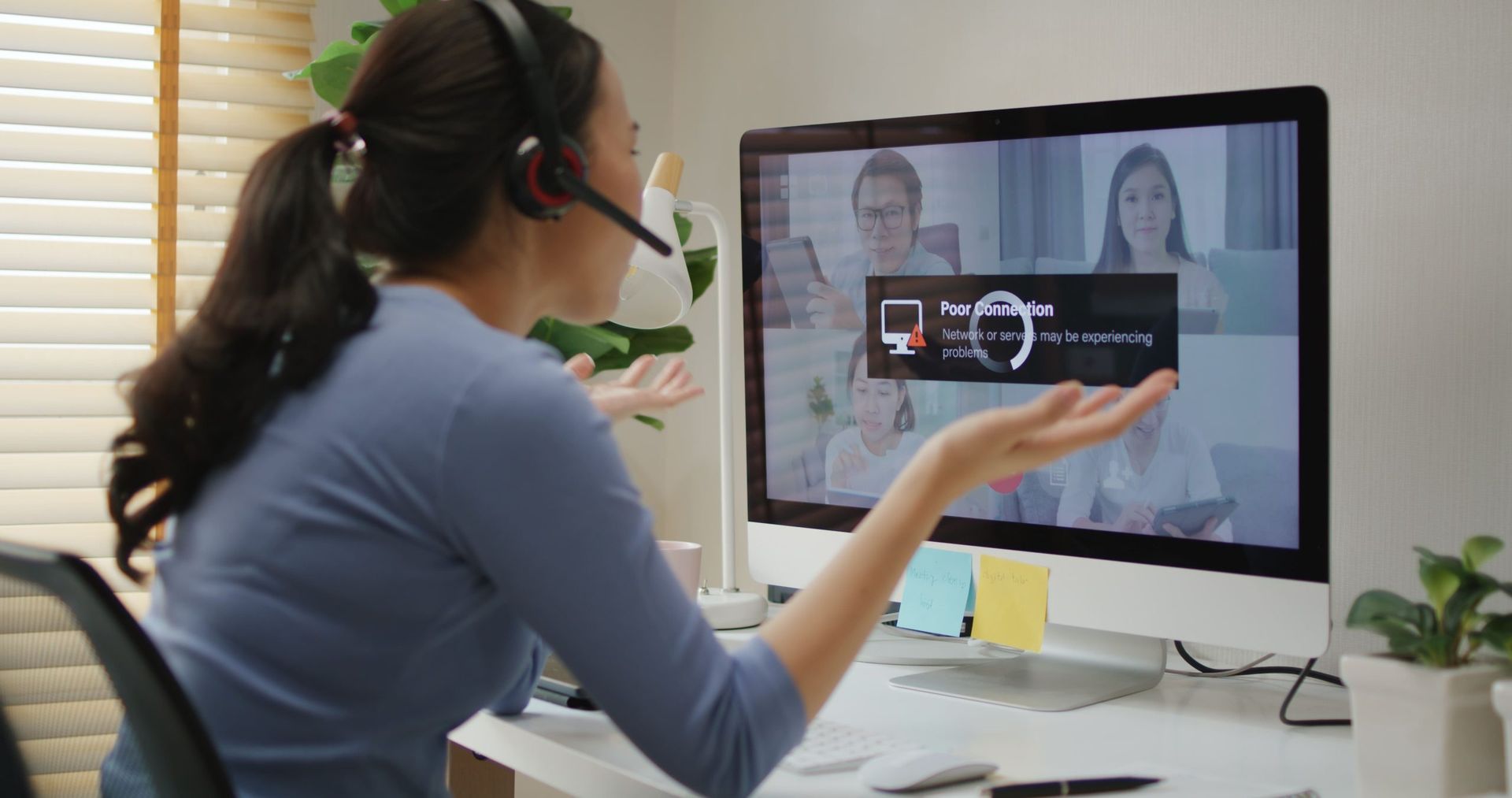 Woman in video call, gesturing with frustration at buffering screen on a computer in home office. Woman in video call, gesturing with frustration at buffering screen on a computer in home office.