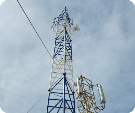 A tall telecommunications tower against a cloudy sky, with blue and white sections and various antennas.