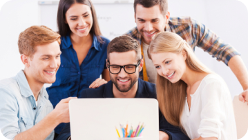 Group of diverse people smiling, gathered around a laptop, appearing to collaborate and share ideas in a bright setting. Group of diverse people smiling, gathered around a laptop, appearing to collaborate and share ideas in a bright setting.