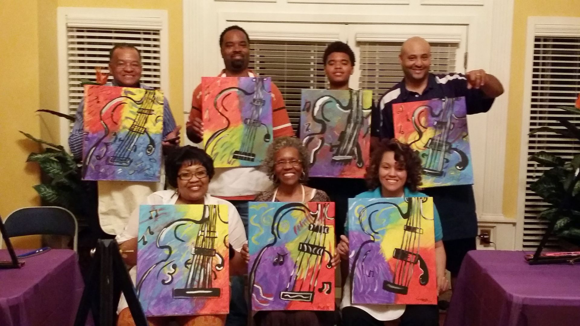 A group of people are posing for a picture with their paintings