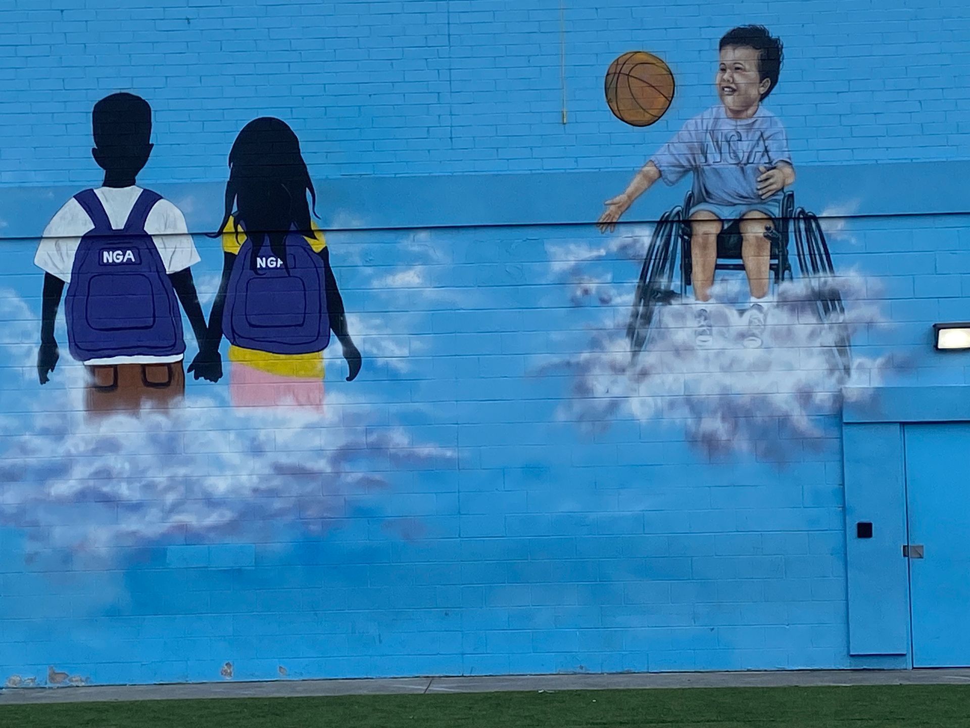 A mural on the side of a building shows a boy playing basketball