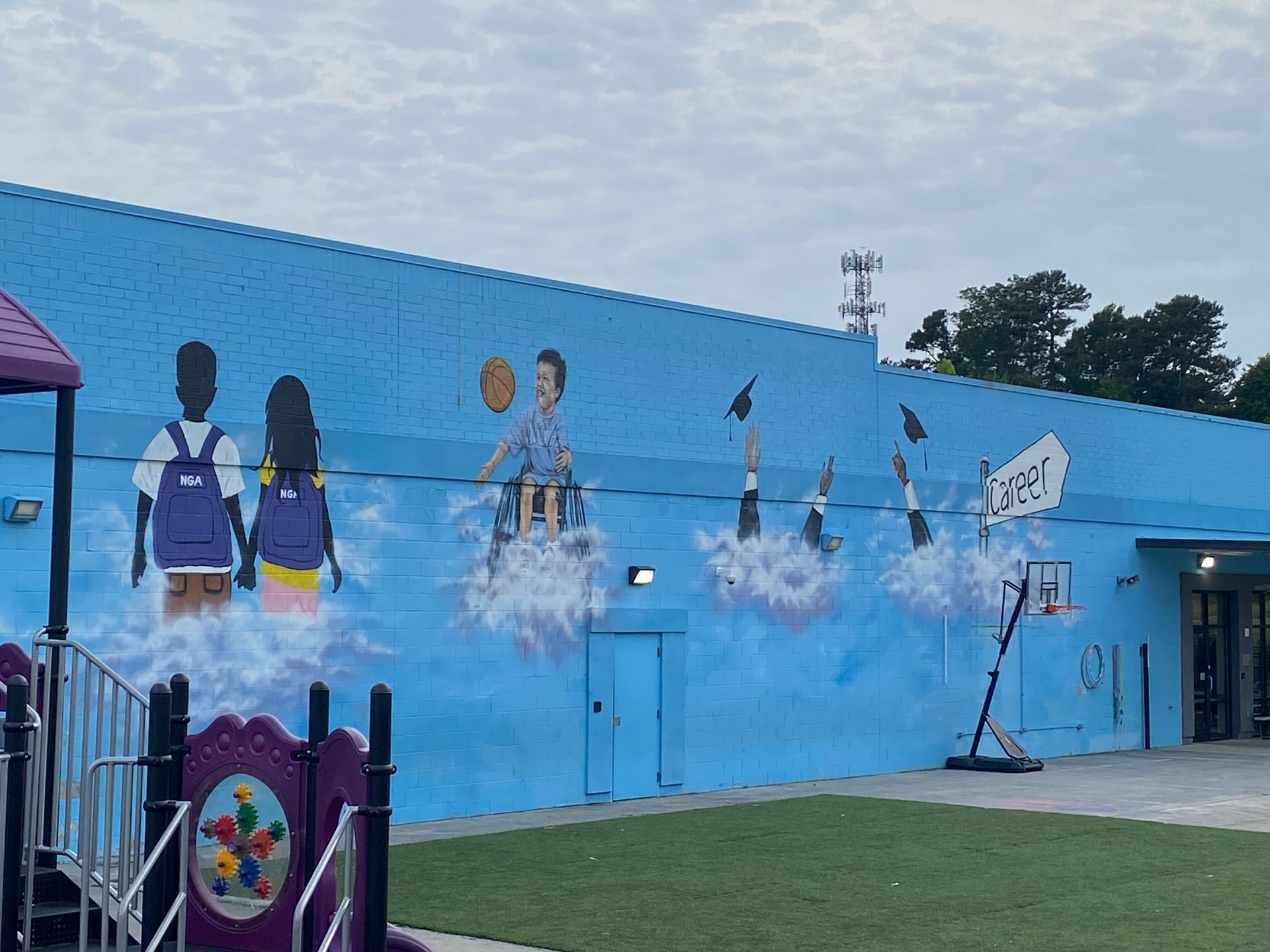 A large mural on the side of a building with a playground in front of it.