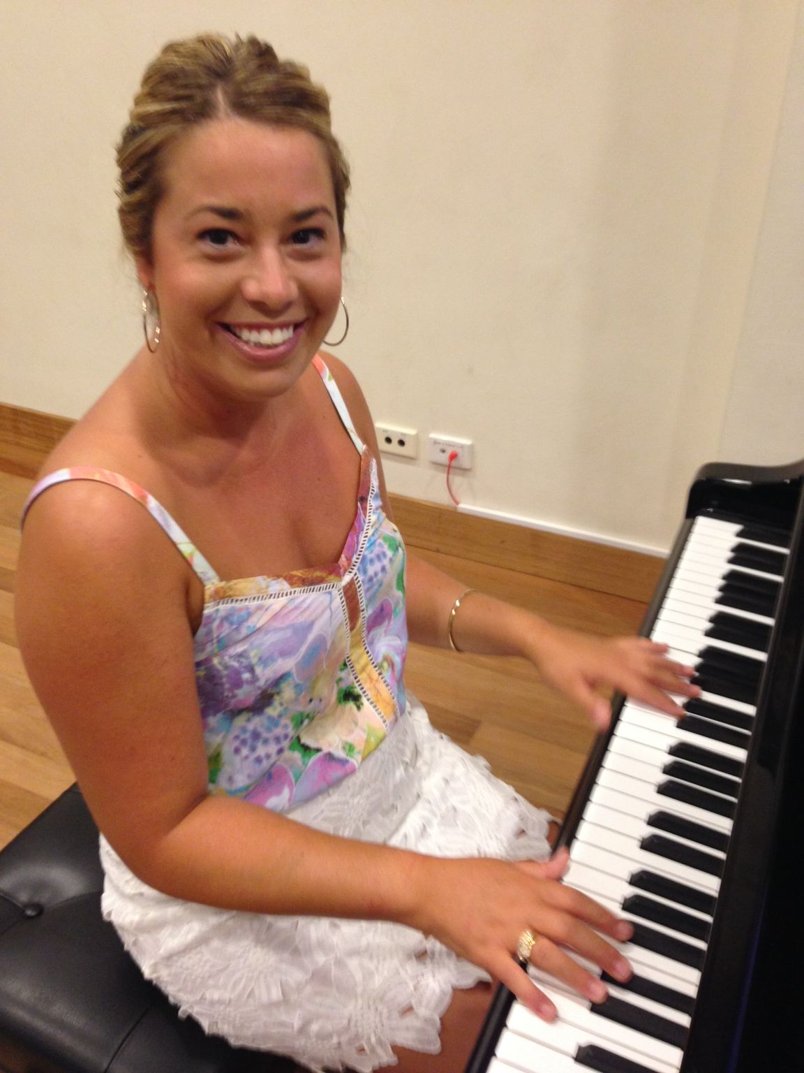 Lindsay Gilroy is smiling while playing a piano