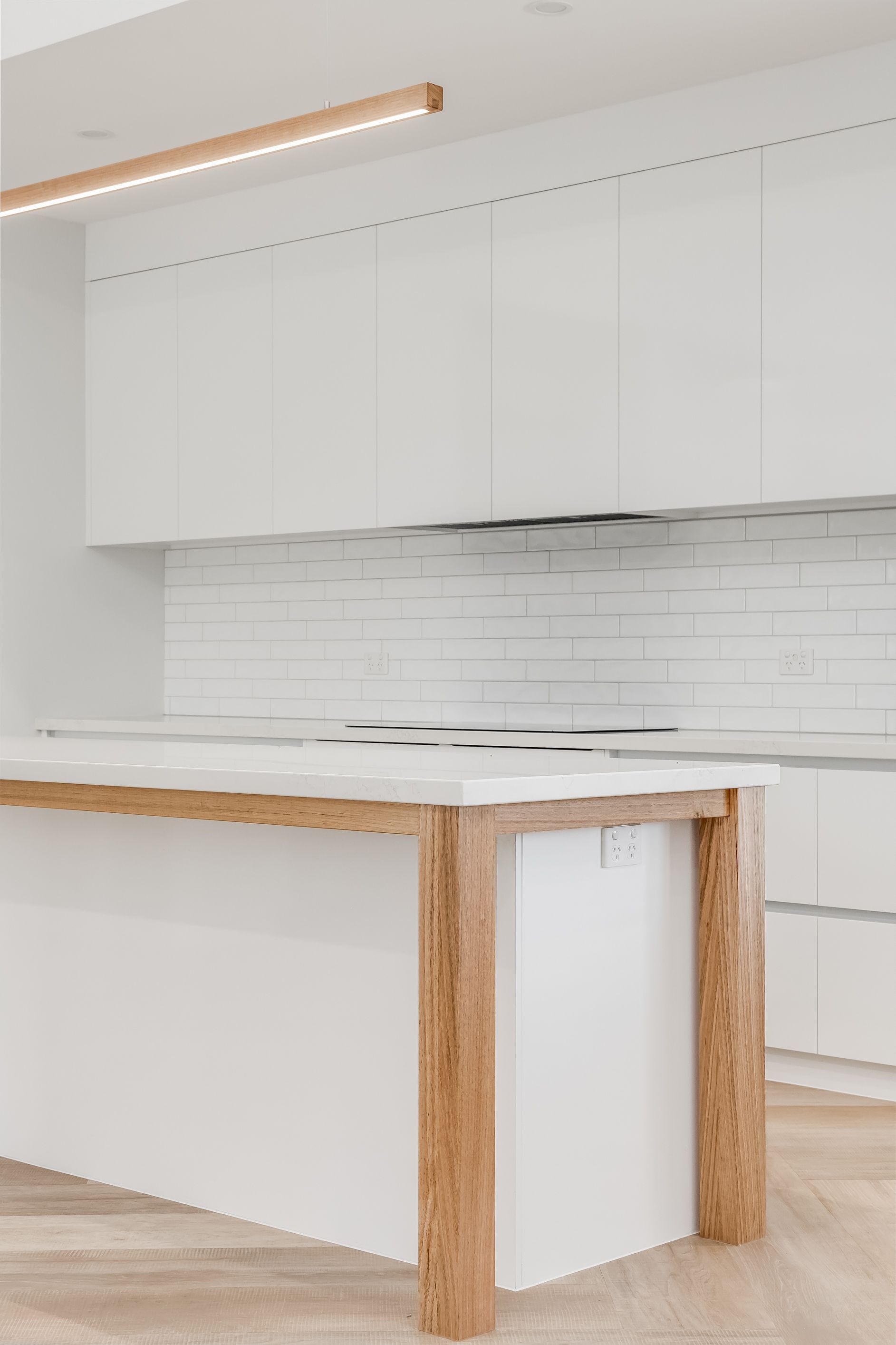 Modern kitchen with white cabinets, marble countertop, white subway tile backsplash, and wood island legs