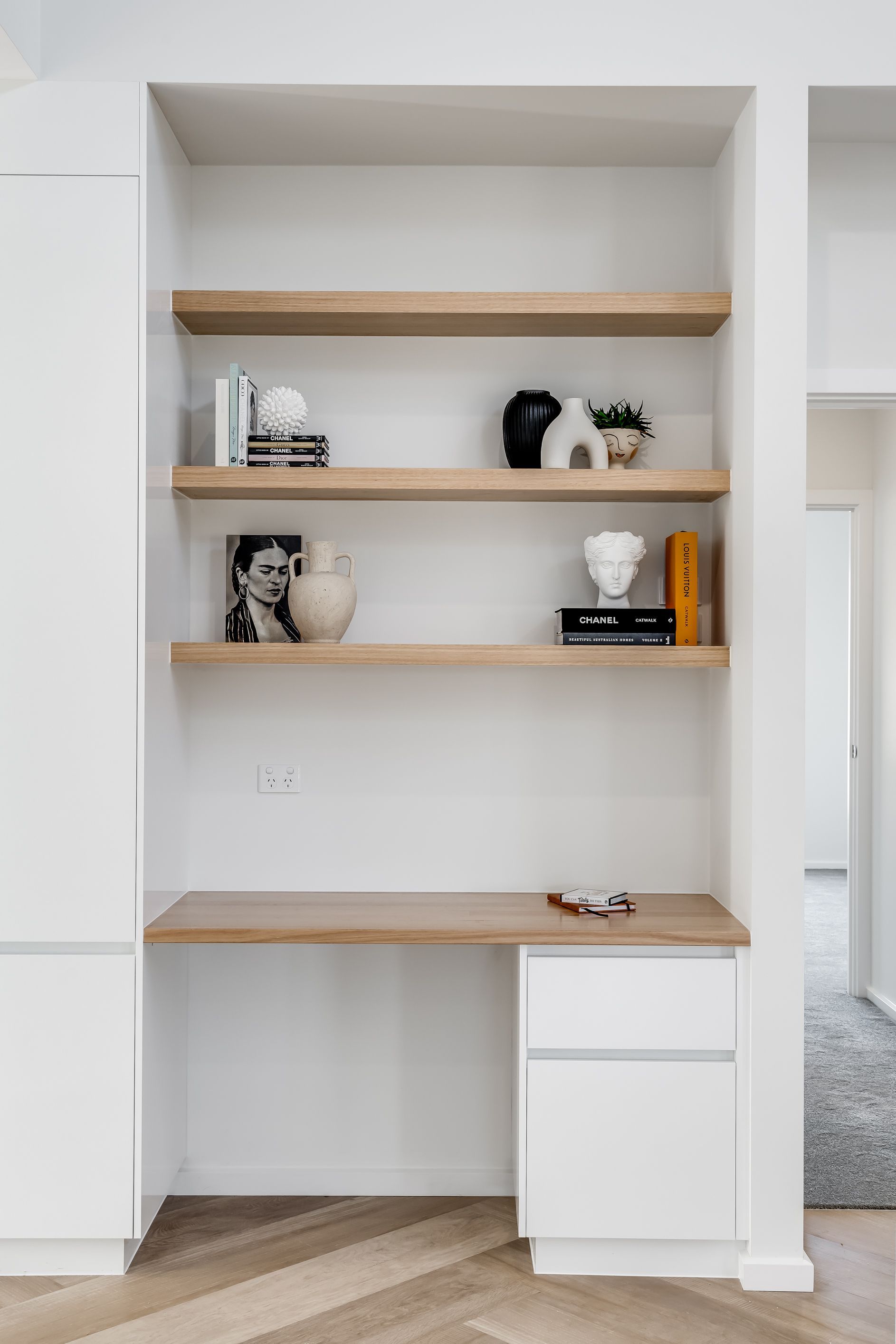 Built-in white bookshelf with wood shelves and decor items in a bright room