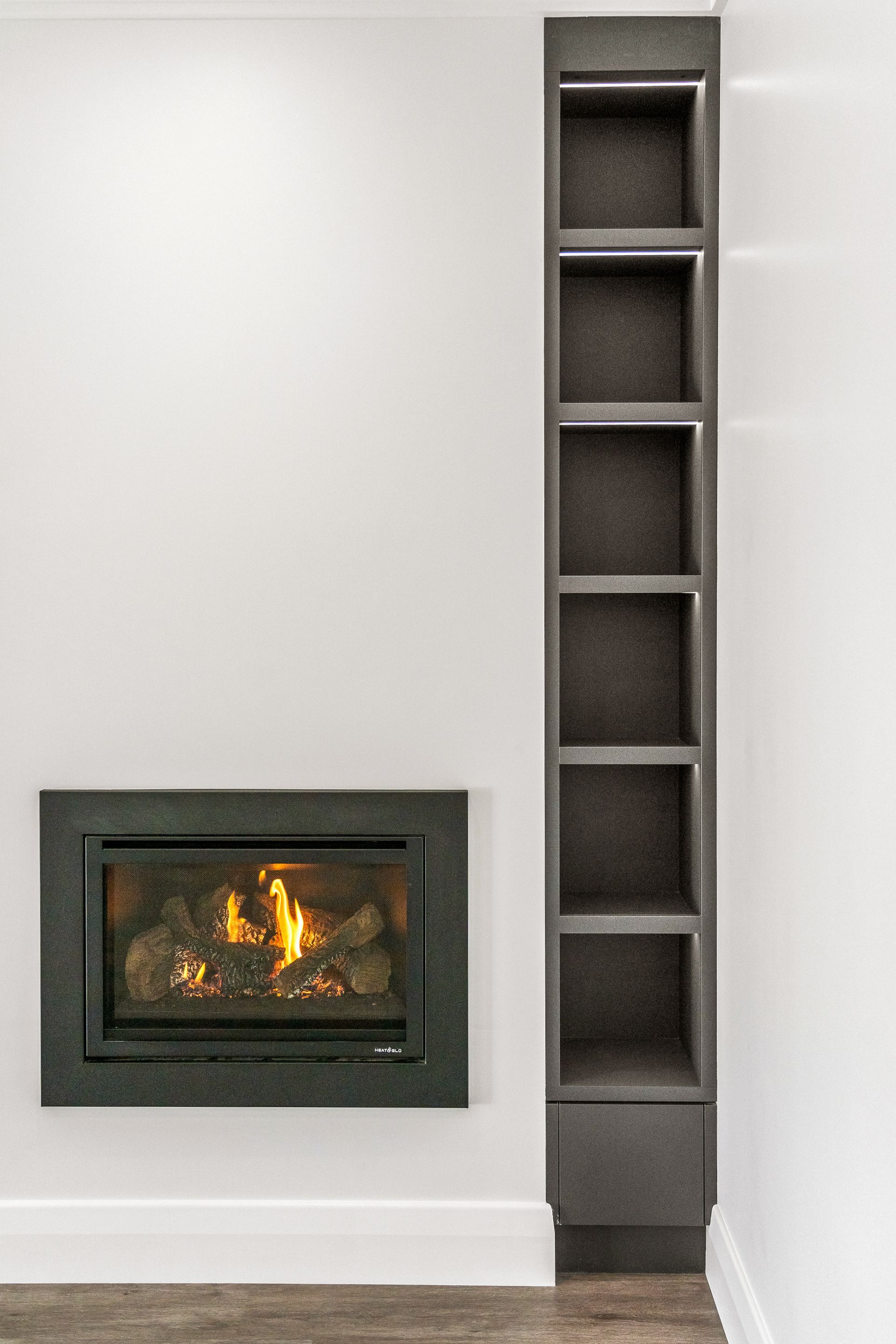 Modern room with a dark fireplace on the left and a tall built-in shelf on the right.