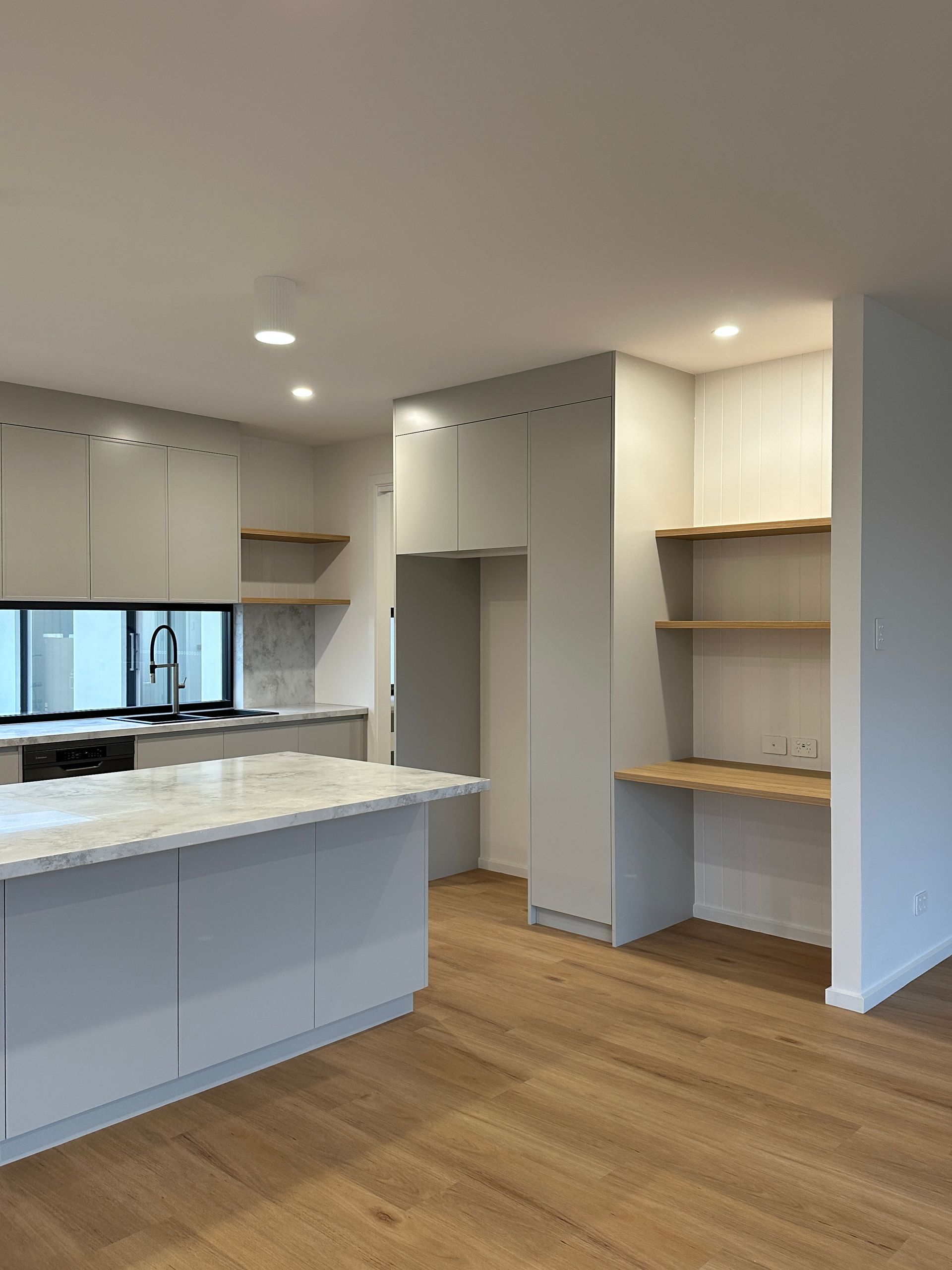 Bright modern kitchen with white cabinets, island, built-in shelves, and wood flooring