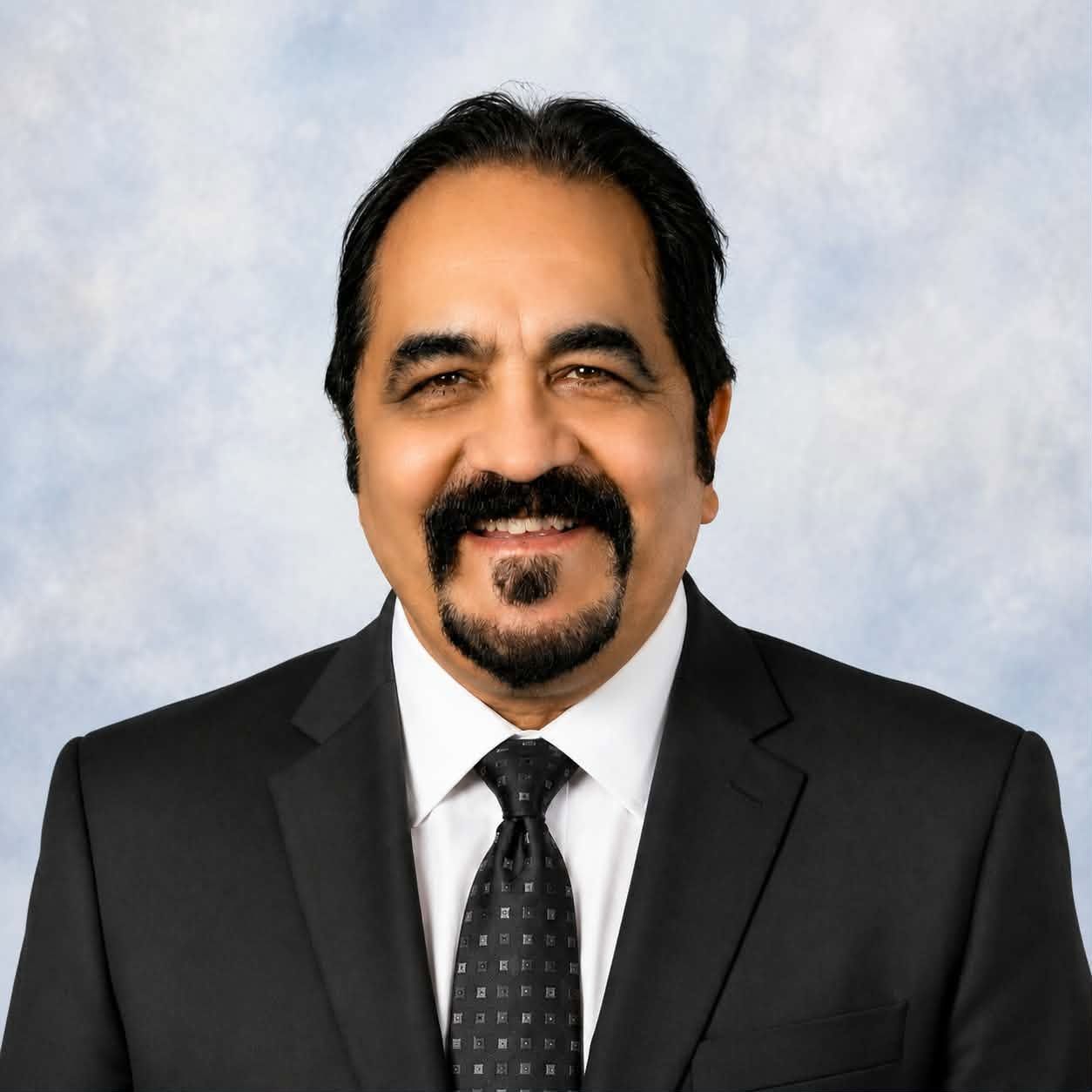 A man in a suit and plaid shirt is smiling for the camera.