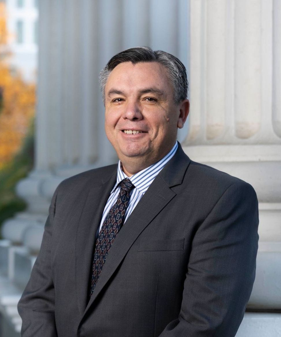 A man in a suit and tie is smiling for the camera