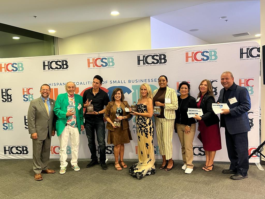 A group of people standing in front of a wall holding awards.