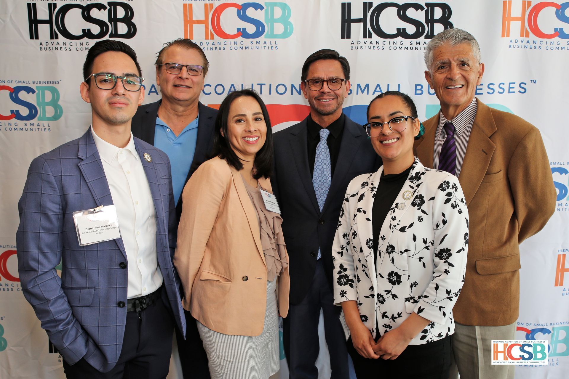 A group of people are posing for a picture in front of a hcsb banner.