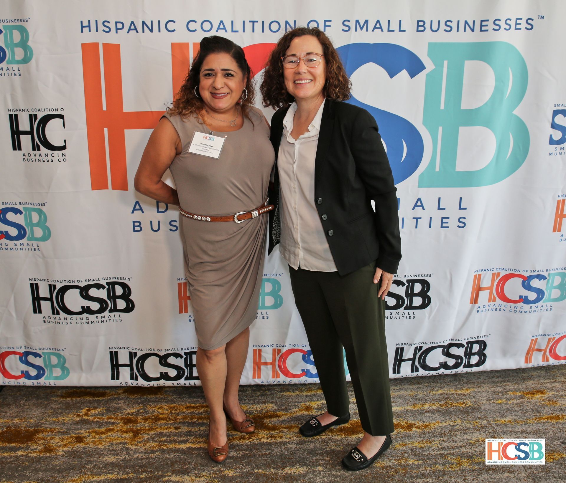 Two women standing in front of a wall that says hispanic coalition of small businesses