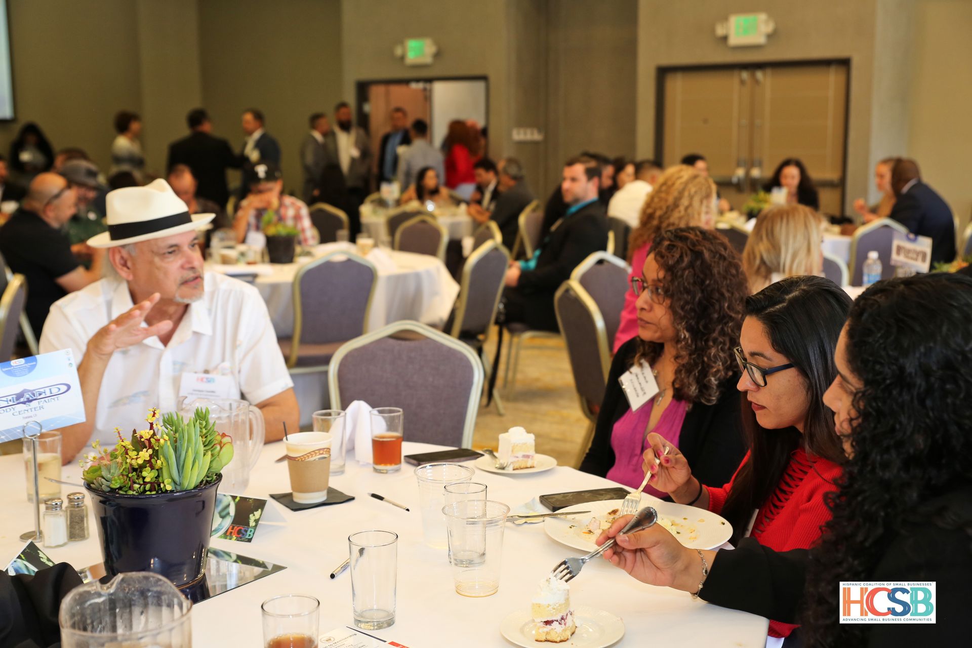 A group of people are sitting at tables in a room eating food.