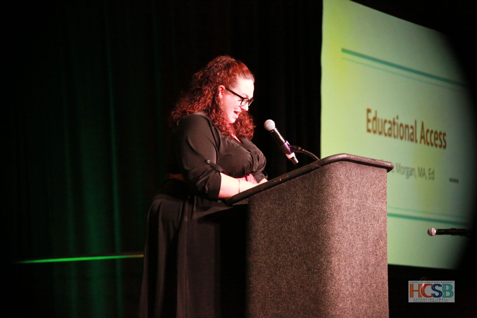 A woman stands at a podium giving a speech about educational access