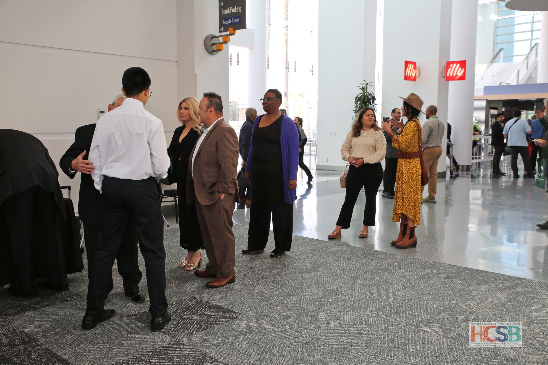 A group of people are standing in a hallway talking to each other.