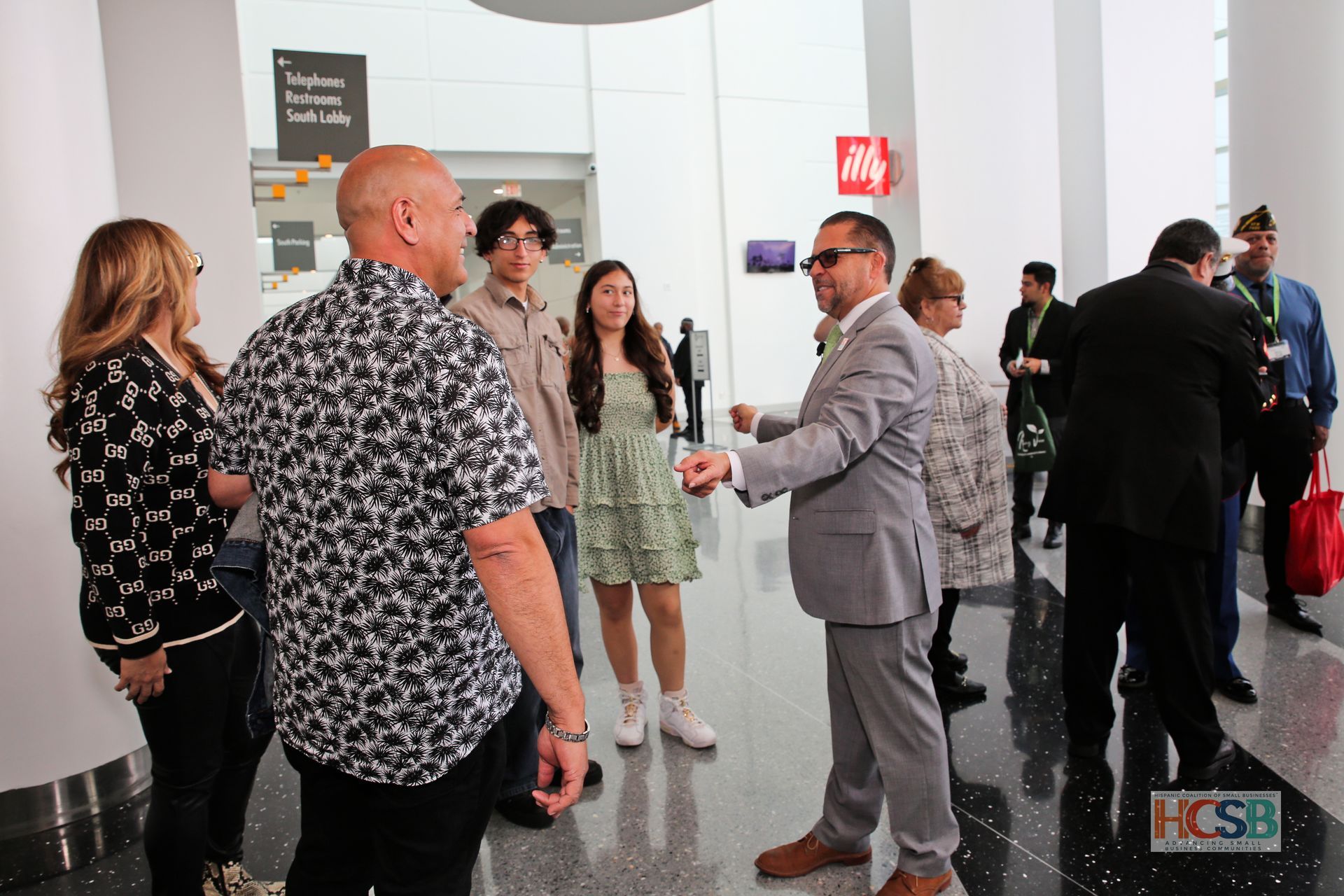 A group of people are standing in a hallway talking to each other.