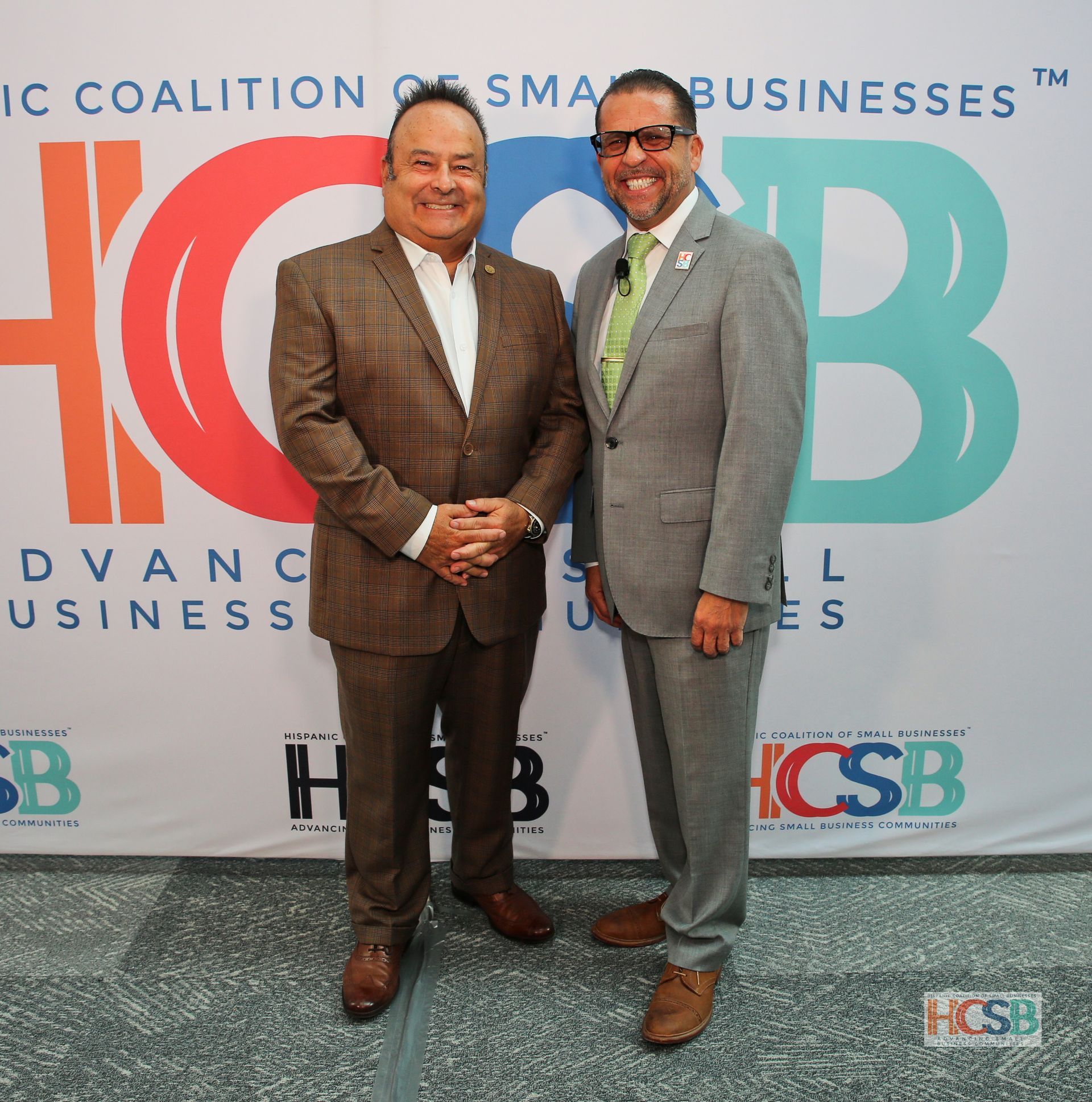 Two men standing in front of a hcsb banner