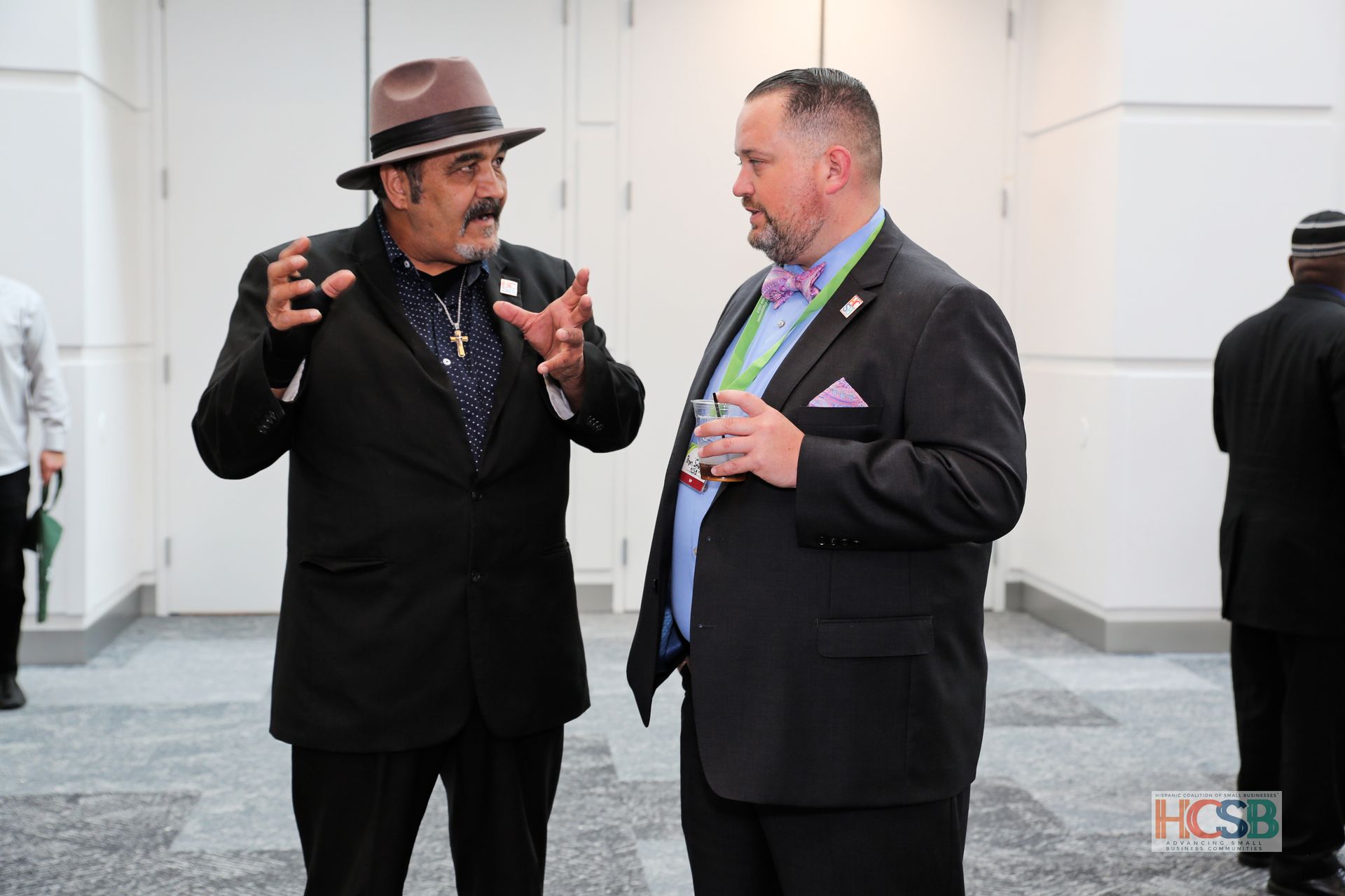 Two men in suits and hats are talking to each other