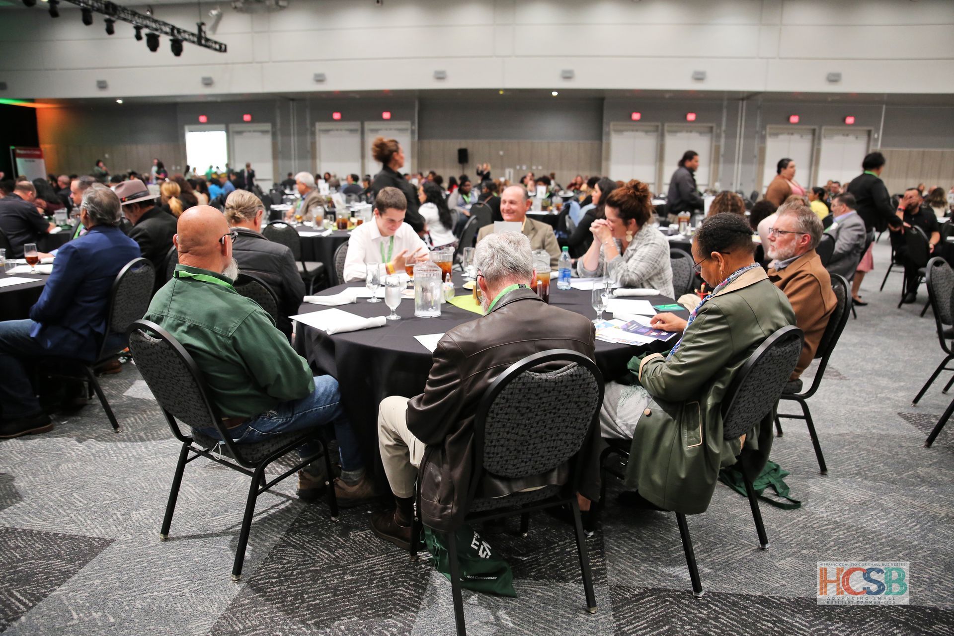 A large group of people are sitting at tables in a large room.