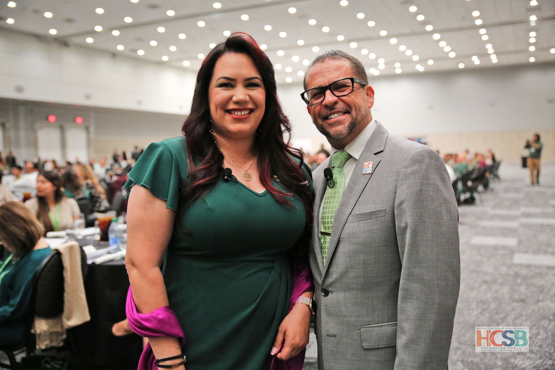A man and a woman are posing for a picture in a large room.