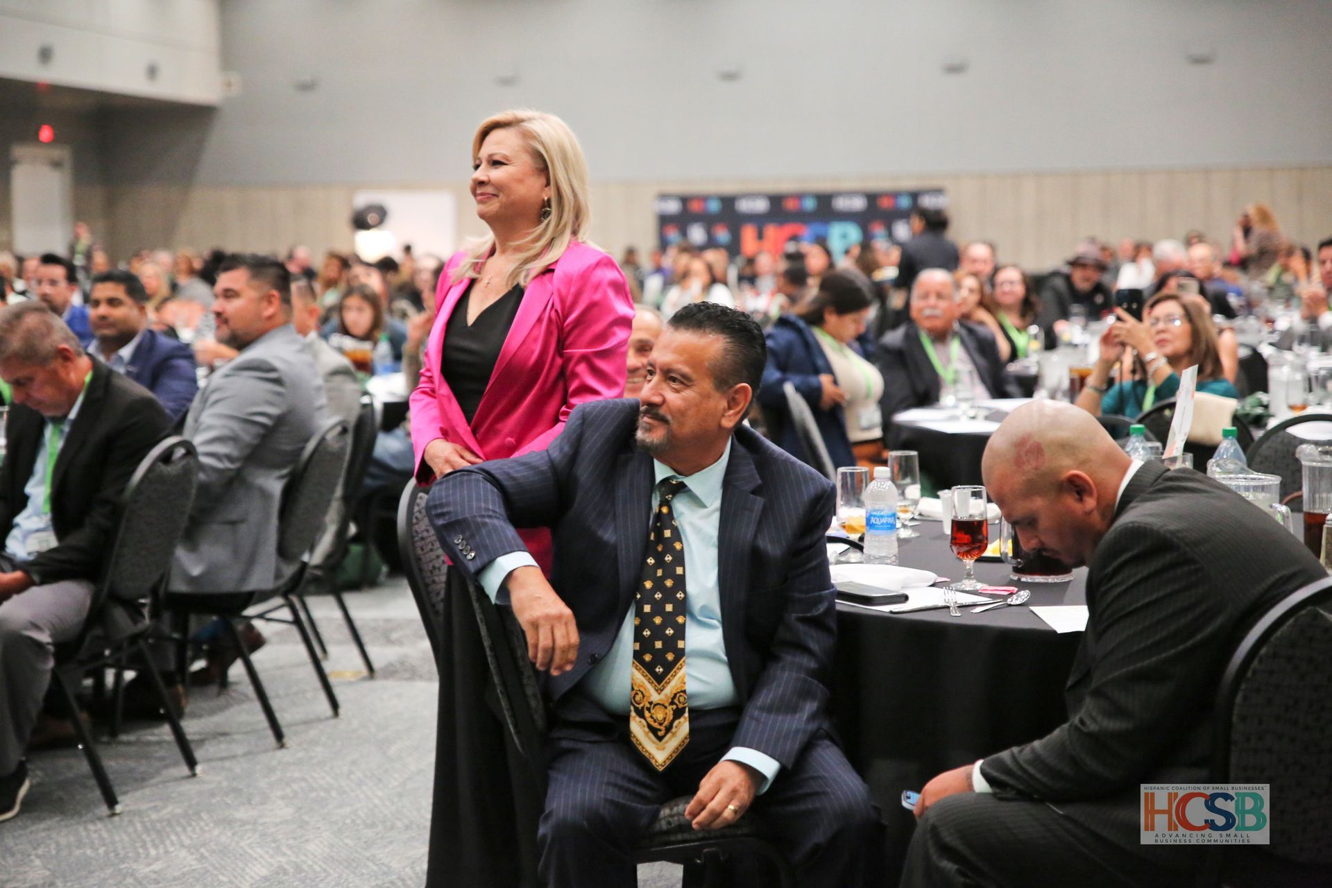 A group of people are sitting at tables in a conference room.
