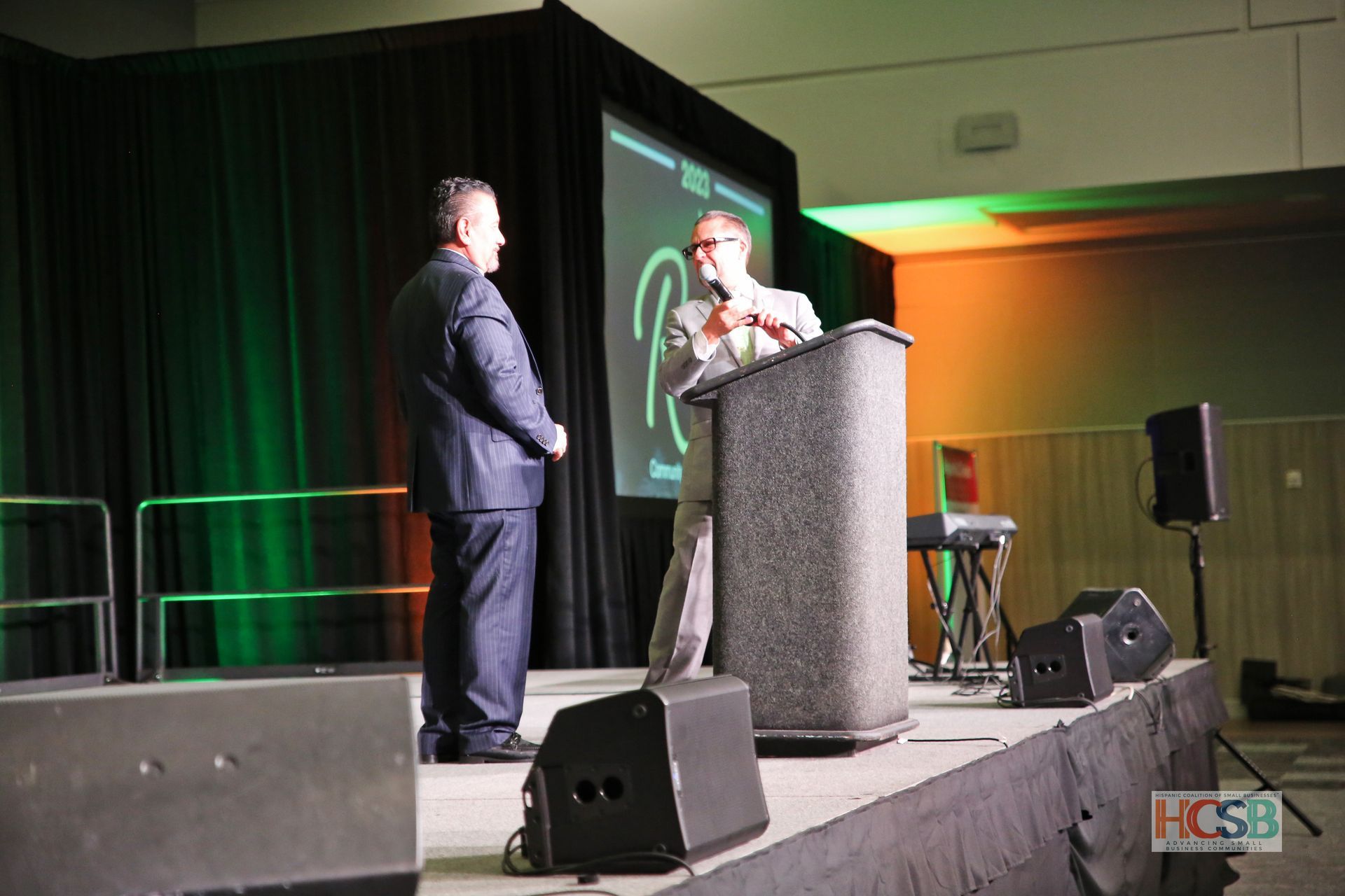 Two men are standing on a stage talking to each other